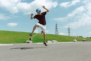 Image showing Skateboarder doing a trick at the city\'s street in sunny day