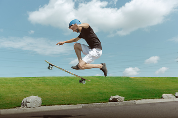 Image showing Skateboarder doing a trick at the city\'s street in sunny day