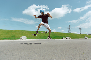 Image showing Skateboarder doing a trick at the city\'s street in sunny day