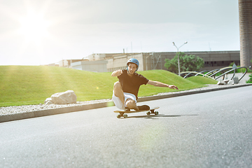 Image showing Skateboarder doing a trick at the city\'s street in sunny day