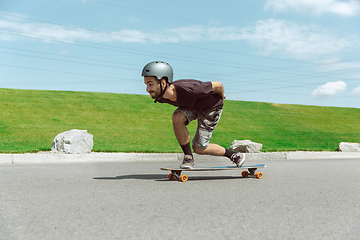 Image showing Skateboarder doing a trick at the city\'s street in sunny day