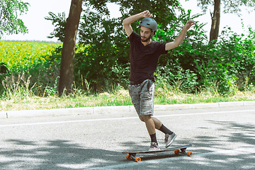 Image showing Skateboarder doing a trick at the city\'s street in sunny day