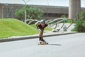 Image showing Skateboarder doing a trick at the city\'s street in sunny day