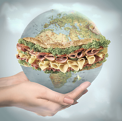 Image showing Save healthy food - female hands holding a globe as a sandwich