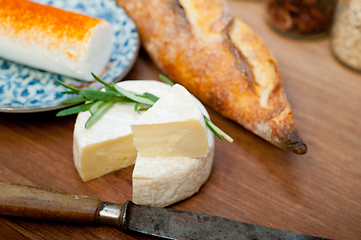 Image showing French cheese and fresh  baguette on a wood cutter