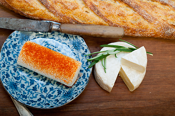 Image showing French cheese and fresh  baguette on a wood cutter