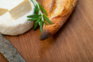 Image showing French cheese and fresh  baguette on a wood cutter