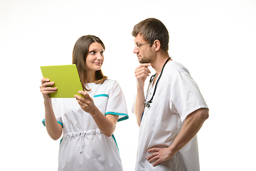 Image showing Doctor looks thoughtfully at a nurse with a tablet computer in his hands