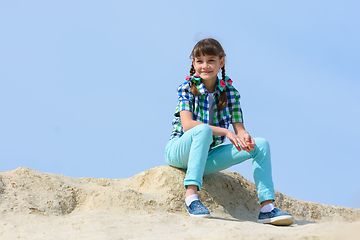 Image showing A ten year old girl sits on a hilltop and smiles