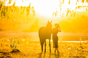 Image showing Girl with a horse on a walk at sunset