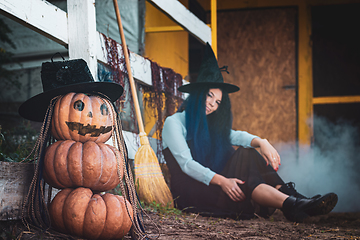 Image showing In the foreground there is a figure of pumpkins with a vicious face, in the background a witch sits