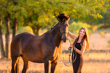 Image showing The girl put a hat on the horse for a walk and happily looked into the frame, portrait