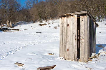 Image showing An old wooden street toilet stands alone on an empty snow-covered plot