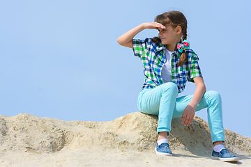 Image showing The girl sits on the top of the hill and looks into the distance