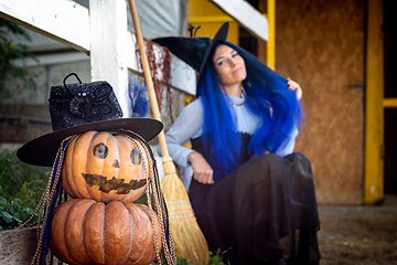 Image showing In the foreground is a figurine of pumpkins, in the background a witch sits by the fence