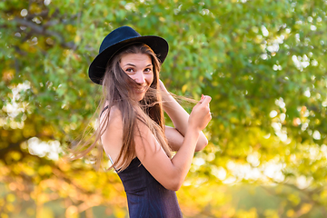 Image showing Portrait of a beautiful girl against a background of blurry foliage, the girl temptingly covered her face with a lock of hair