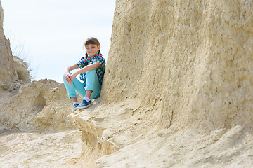 Image showing Girl in casual clothes sits on a cliff ledge