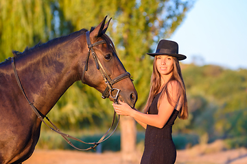 Image showing The girl stands in front of the horse and turned and looked into the frame