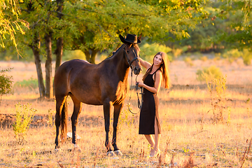 Image showing The girl put a hat on the horse for a walk and happily looked into the frame