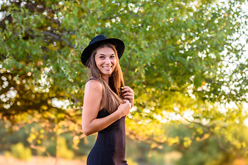 Image showing Portrait of a beautiful cheerful smiling girl on a background of blurry foliage