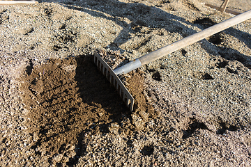 Image showing Rakes loosen the garden bed during the spring work on the personal plot