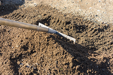 Image showing The rake loosens and levels the fertile soil