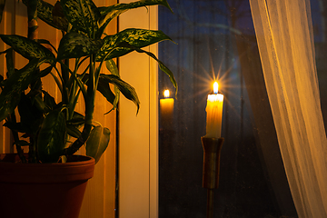 Image showing A lonely candle stands by the window in the evening as a token of memory of those who died in wars