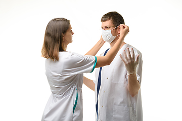 Image showing The nurse puts a medical mask on the doctor\'s face