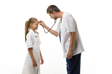 Image showing The doctor put the head of the phonendoscope to the forehead of the girl in a medical gown