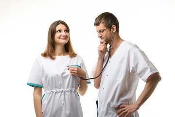 Image showing The doctor listens with interest to the girl\'s heart with a phonendoscope