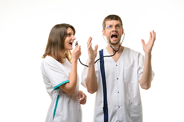 Image showing Girl doctor screams into the head of the phonendoscope worn by the doctor, the doctor screams from a loud sound