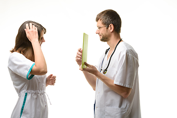 Image showing The intern is thinking about the question of the tablet computer shown by the doctor