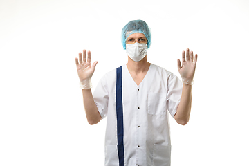 Image showing A male doctor stands with his hands raised up, gloves are on, a mask and a hat are on his head