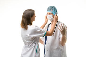 Image showing Nurse putting medical mask on surgeon face isolated on white