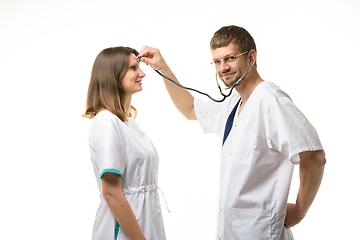 Image showing The doctor put the voice of the phonendoscope to the head of the doctor\'s girl and listens with interest to her thoughts
