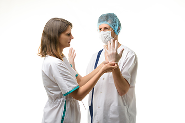 Image showing A nurse puts sterile medical gloves on the surgeon\'s hands