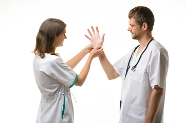 Image showing A nurse helps a doctor put on rubber sterile gloves