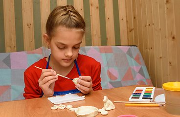 Image showing A girl at home paints figures from salt dough