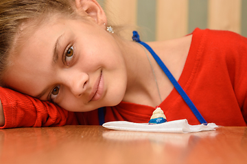 Image showing The girl laid her head on her hand and looked into the frame, painting dough figurines at the table