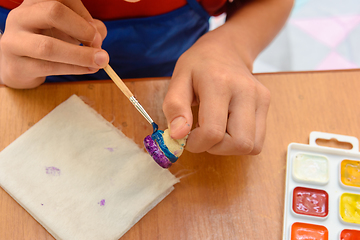 Image showing A girl paints a figurine made of salt dough with a brush