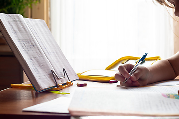 Image showing Child\'s hand writes in a notebook while doing homework, close-up