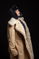 Image showing Portrait of a Caucasian-looking man in a Soviet officer\'s fur hat and an army sheepskin coat, standing at attention