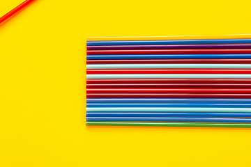 Image showing On a yellow background, there are a dozen multi-colored cocktail tubes, in the corner there is another tube
