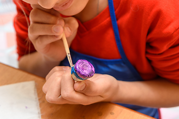 Image showing Paints a figurine of salt dough for a girl in class