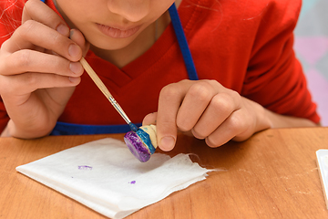 Image showing A girl paints a figurine made of salt dough with a brush, close-up