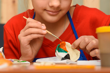 Image showing A girl paints a craft from salt dough with watercolors, close-up