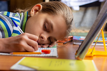 Image showing Girl from fatigue put her head on the table doing homework