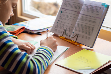 Image showing Girl at home in front of the window doing homework