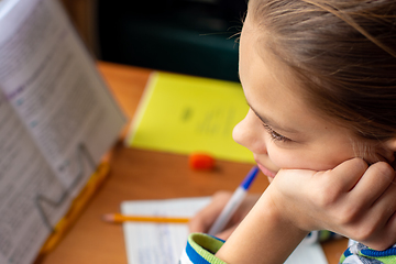 Image showing Close-up of a girl doing homework, a girl lost in thought distracted from the task