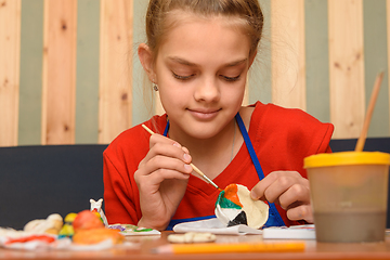 Image showing A girl paints a craft from salt dough with watercolors